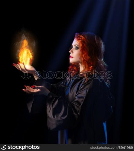 Young witch with flame on blue rays background
