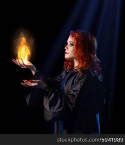 Young witch with flame on blue rays background