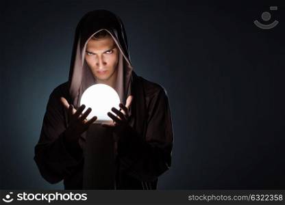 Young wizard with crystal ball in dark room. The young wizard with crystal ball in dark room
