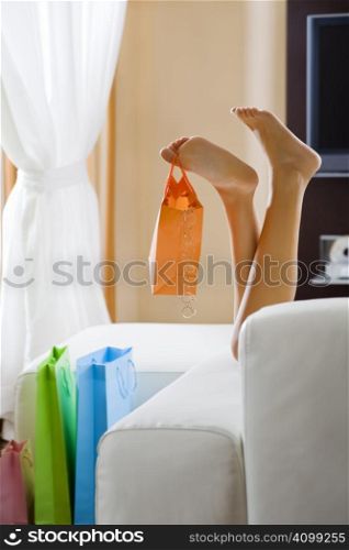Young woman&acute;s legs dangling shopping bag