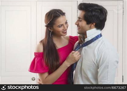 Young woman adjusting husband's tie
