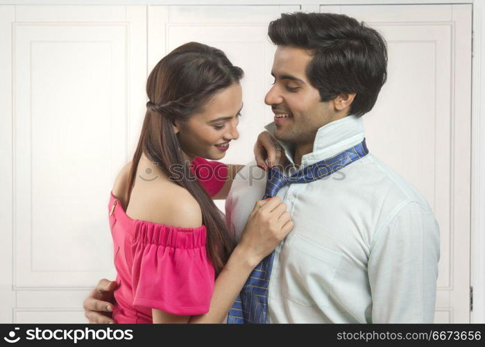 Young woman adjusting husband's tie