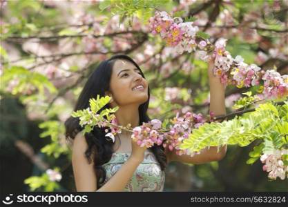 Young woman admiring flowers on a branch