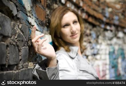 Young Woman Against A Brick Wall. Focus On Hand.