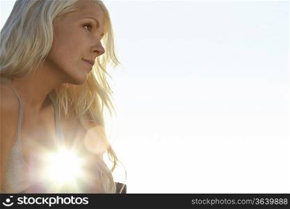 Young woman against sun, close up, low angle view