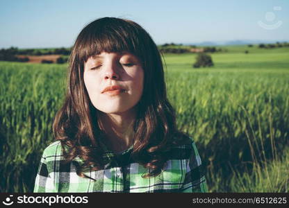 Young woman alone in a green field in a sunny day