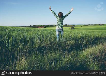 Young woman alone in a green field in a sunny day