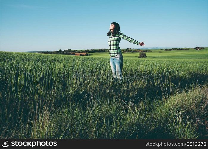 Young woman alone in a green field in a sunny day