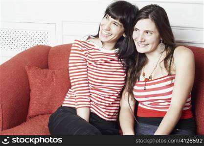Young woman and a mid adult woman sitting on a couch and smiling