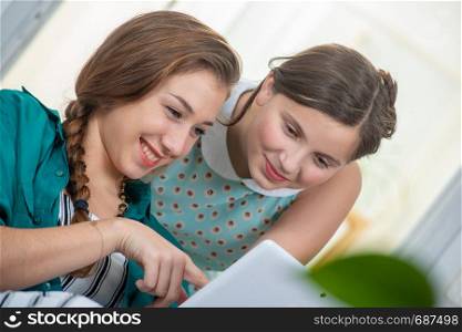 young woman and a teen girl using tablet computer at home