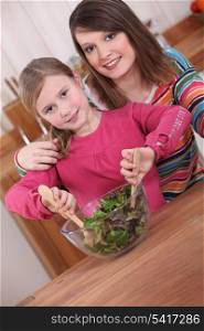 Young woman and daughter mixing salad