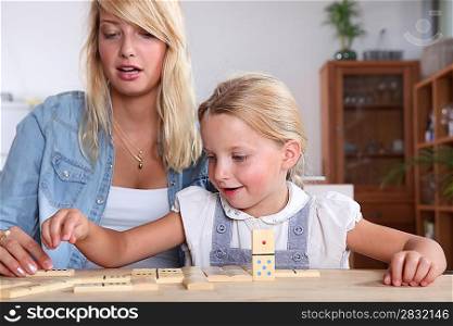 Young woman and her daughter playing dominoes