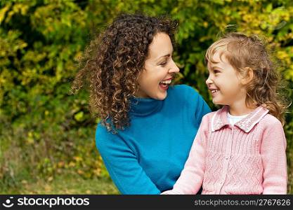 young woman and little girl laugh in garden
