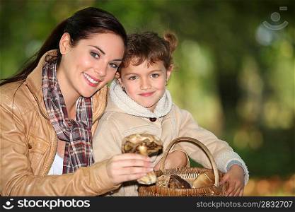 Young woman and little girl picking mushrooms in the countryside
