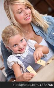 Young woman and little girl playing with dominoes