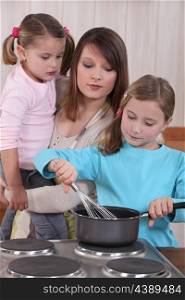 Young woman and little girls preparing a cake