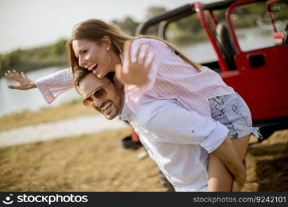Young woman and man having fun outdoor near car at summer day