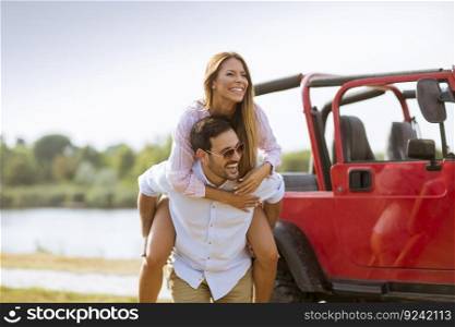 Young woman and man having fun outdoor near car at summer day