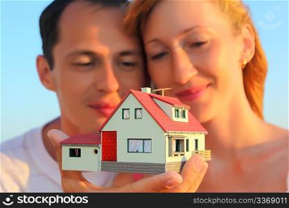 Young woman and man keeping in hands model of house with garage