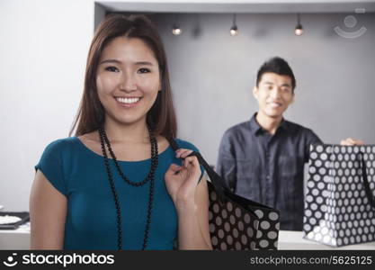 Young woman and man with shopping bags at fashion store, portrait