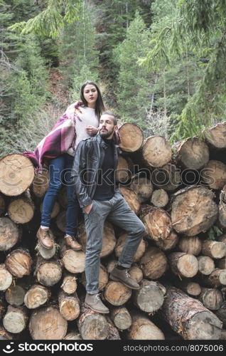 Young woman and men on wood logs in the forest