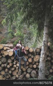 Young woman and men on wood logs in the forest
