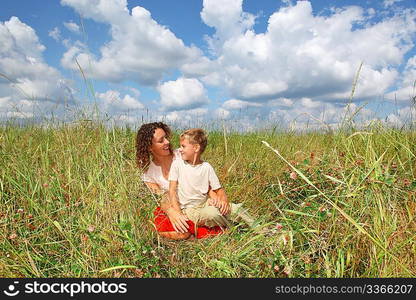 young woman and smiling boy sitting on meadow, Looking against each other