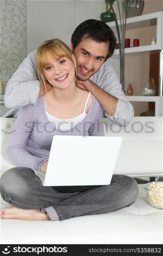 Young woman and young man smiling with laptop at home