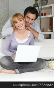 Young woman and young man smiling with laptop at home