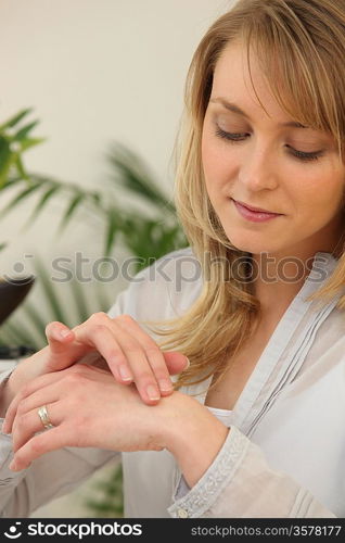 Young woman applying cream on her hand