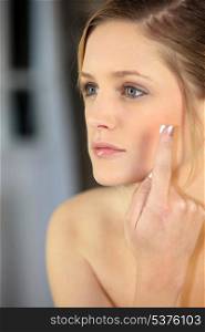 Young woman applying facial cream