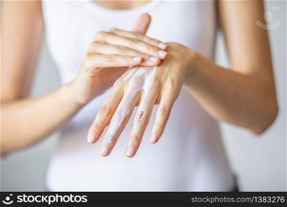 Young woman applying hand cream to care and protect skin, close up.