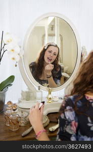 Young woman applying lipstick