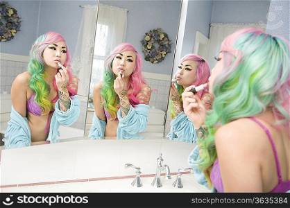 Young woman applying lipstick on her lips with multiple mirror reflections