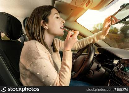 Young woman applying make up in car