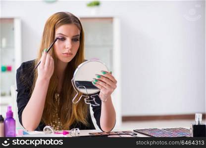Young woman applying make-up preparing for party