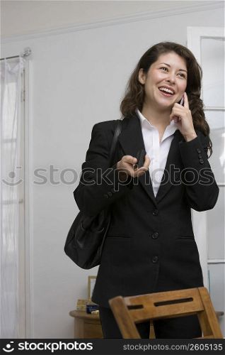 Young woman applying makeup while chatting on cell phone