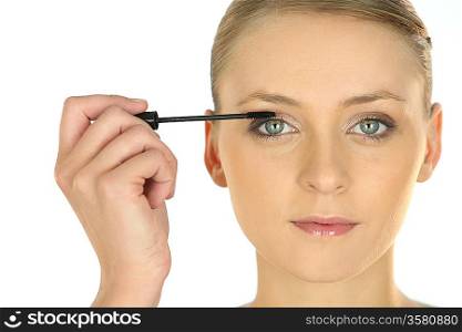 Young woman applying mascara