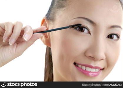 Young woman applying mascara, portrait