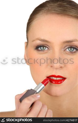 Young woman applying red lipstick