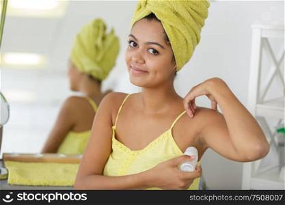 young woman applying roller deodorant in her armpit