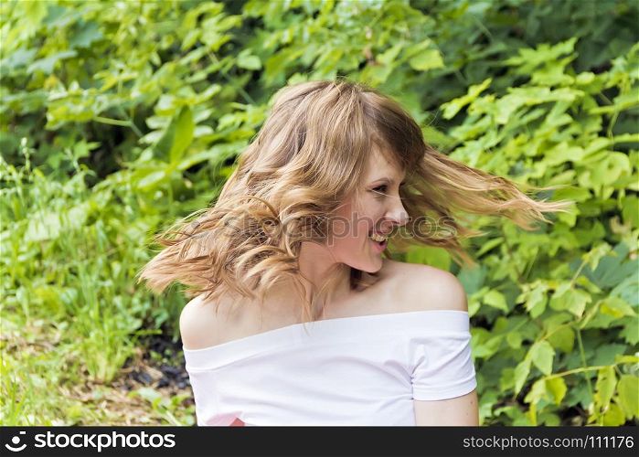 Young woman are playing with own blond hair on summer background