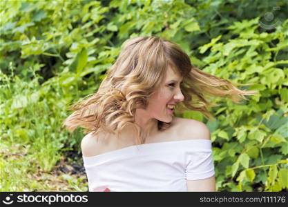 Young woman are playing with own blond hair on summer background