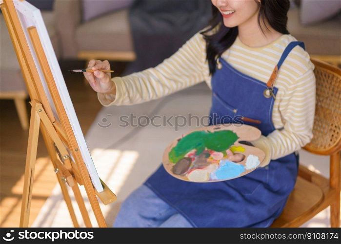 Young woman artist is imagination and creating to painting picture in canvas on easel at art studio.