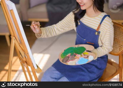 Young woman artist is imagination and creating to painting picture in canvas on easel at art studio.