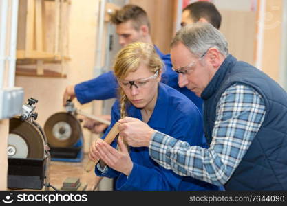 young woman as apprentice in wood processing at guitar workshop