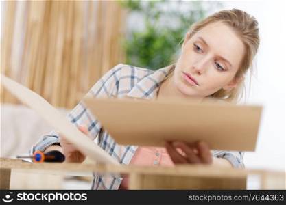 young woman assembling wood furniture