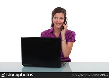 Young woman at a desk with laptop and phone