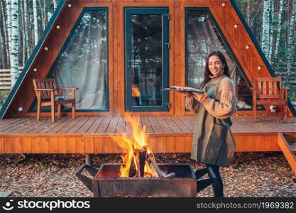 Young woman at autumn warm day grill outdoors. Happy woman in autumn grilled