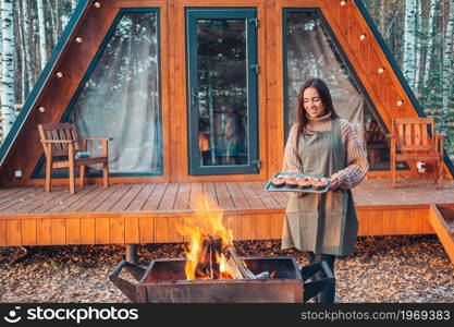 Young woman at autumn warm day grill outdoors. Happy woman in autumn grilled